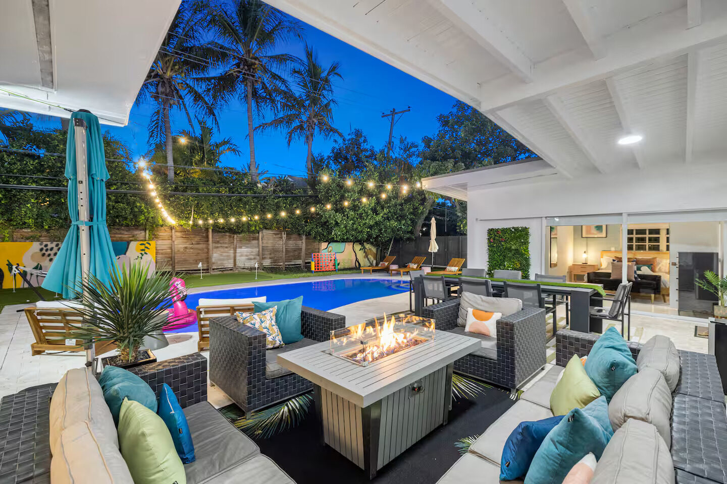 Backyard pool with fire pit and string lights at twilight at the 5BR villa