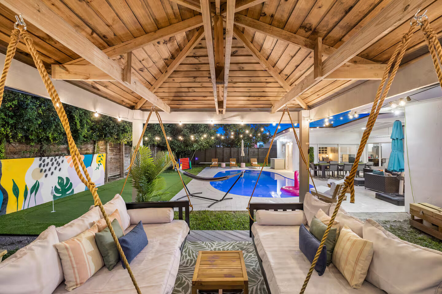 Covered patio with rope-hung swing daybeds overlooking the pool